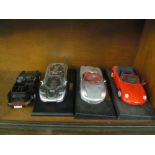 Four Maisto model cars (three on stands)