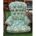 A button upholstered chair in green and white floral fabric