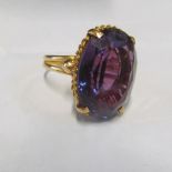 A gold coloured ring with purple stone