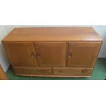 An Ercol Golden Dawn sideboard three cupboard doors above two drawers