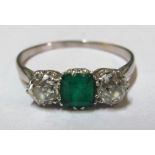 A three stone emerald and diamond ring on platinum band