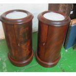 A pair of mahogany cylinder bedside cabinets with marble tops