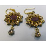 A pair of Indian yellow metal ruby and diamond star shaped earrings with red and green enamel backs