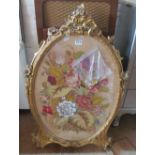 An oval needlework in gilt frame (a/f)