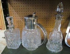 Two silver coloured decanters (replacement stoppers) and a glass jug with plated lid and handle