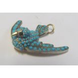 A turquoise set pendant of a bird with red gem set eyes