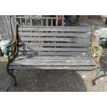 A slatted garden bench with metal supports and lion mask arms