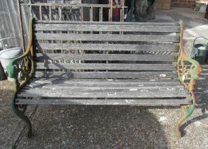 A slatted garden bench with metal supports and lion mask arms