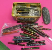 Various coloured mottled cased pens in tin