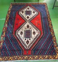 A blue and red ground Persian rug with central cream medallions surrounded by animals and