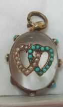 A glass pendant with pearl and turquoise double heart and border