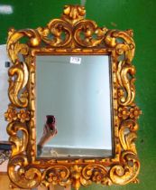 A rectangular mirror with decorative floral and scroll frame