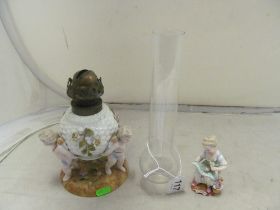 A porcelain oil lamp three cherubs supporting ball and 19th Century figure