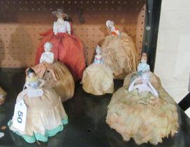 A crinoline lady with purple hat and seven other crinoline ladies all with decorative skirts