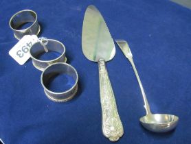 Three silver napkin rings, silver ladle and a cake slice