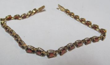 A yellow metal bracelet red stones, marked 10k 5.5g