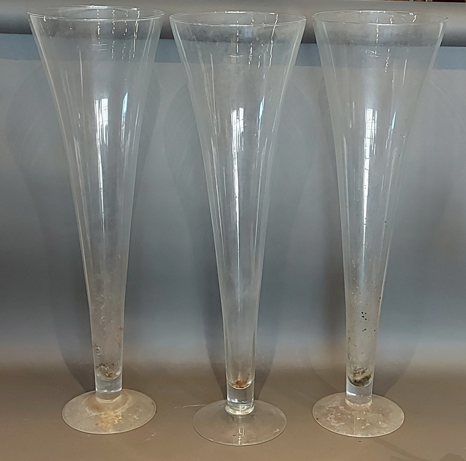 A set of three large glass spill vases of tapering form, 80cms tall