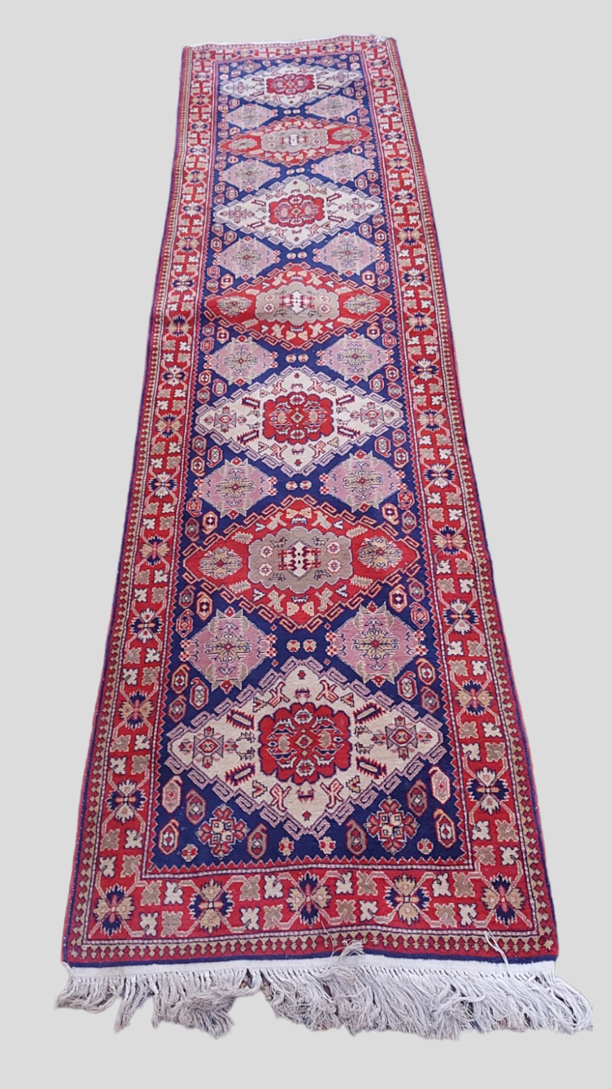 A North west Persian woollen runner with an all over design upon a blue, red and cream ground within