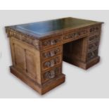 A Victorian carved oak twin pedestal desk, the tooled leather inset top above nine drawers with