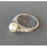 An 18ct white gold ring set with a central pearl flanked by diamond shoulders, 6.5gms