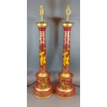 A pair of Toleware table lamps, each with gilded decoration upon a red ground, 60cms tall