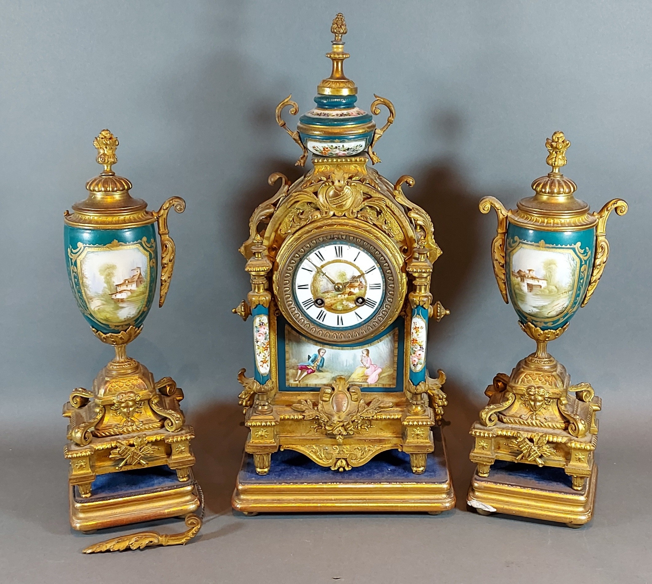 A French spelter and porcelain mounted three piece clock garniture, the clock with two train