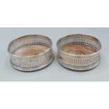 A pair of London silver bottle coasters of pierced form, 9.5cms diameter