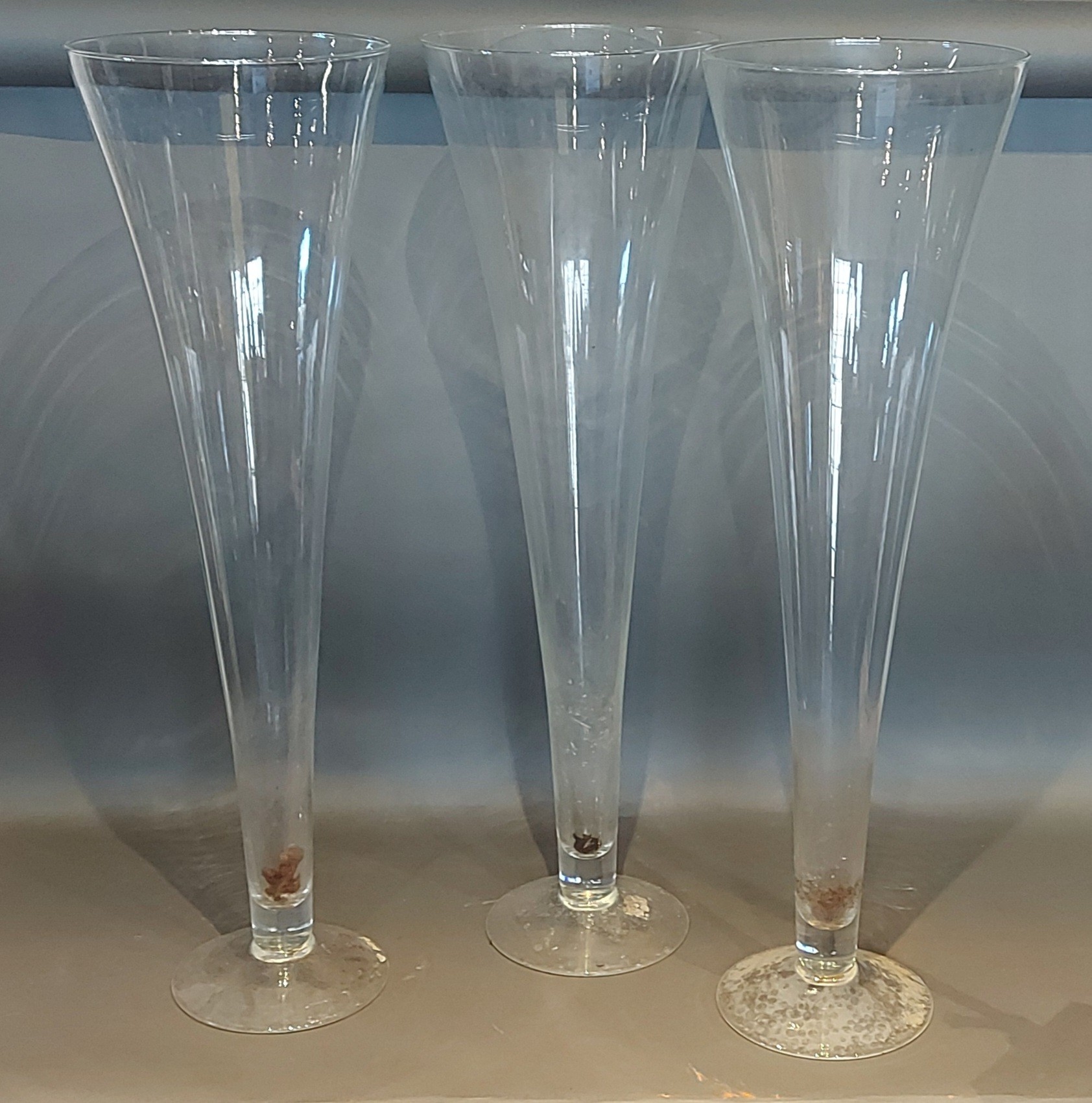 A set of three large glass spill vases of tapering form, 80cms tall