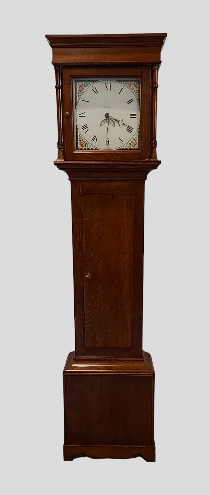 A George III oak longcase clock, the square hood with turned uprights above a rectangular door,