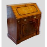 An oak bureau, the fall front enclosing a fitted interior above a frieze drawer and cupboard door