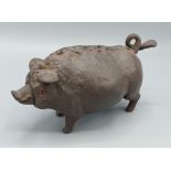A cast iron clockwork desk bell in the form of a pig 17cm long
