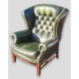 A green leather button upholstered wingback armchair with square legs and stretchers