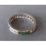 A white metal diamond and emerald set eternity ring, 5gms