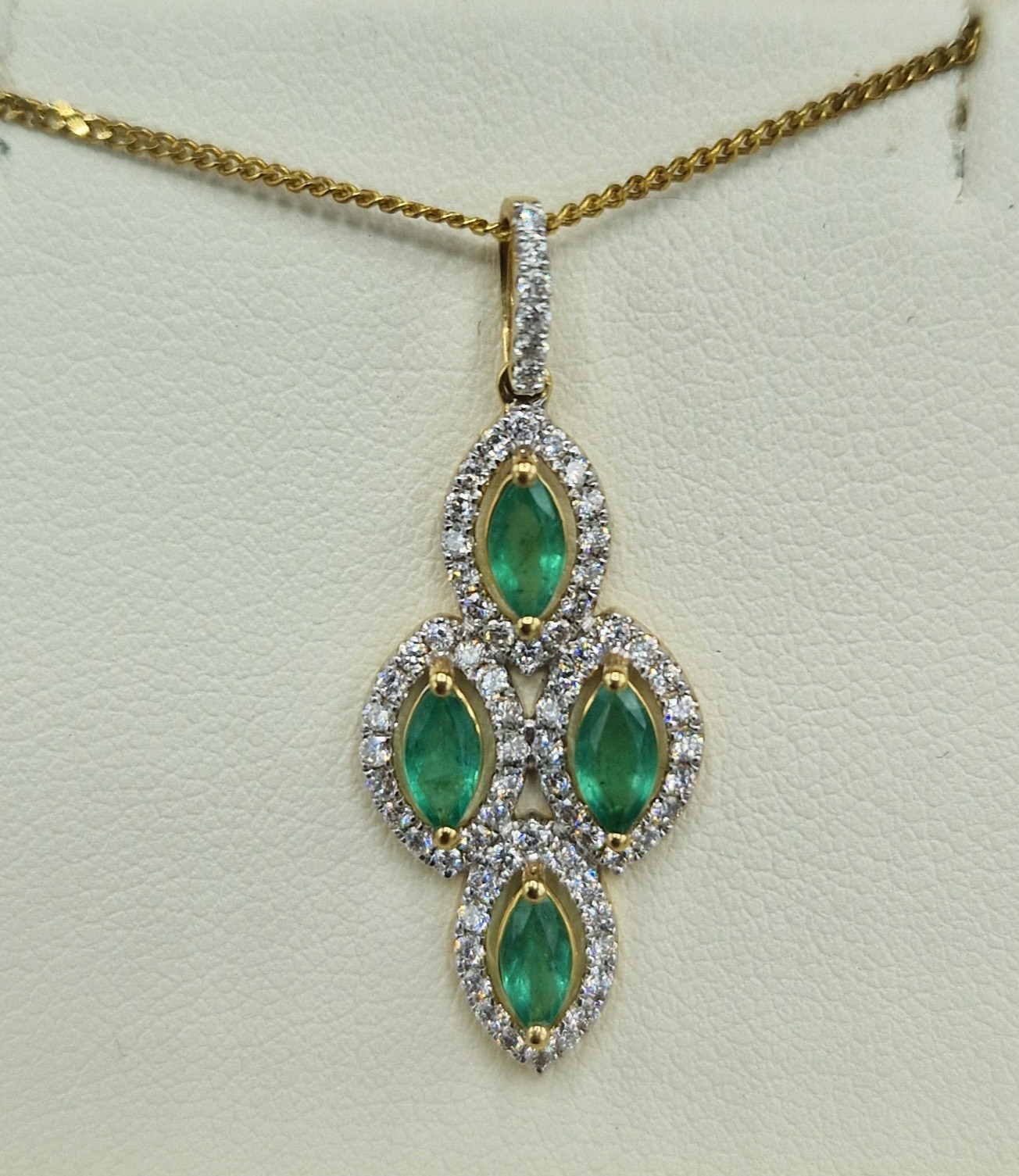 An 18ct gold pendant set with four emeralds surrounded by diamonds with a 925 silver chain, 32mm