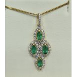 An 18ct gold pendant set with four emeralds surrounded by diamonds with a 925 silver chain, 32mm