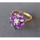 An 18ct gold ring set with a central diamond surrounded by Amethysts, 6.5gms