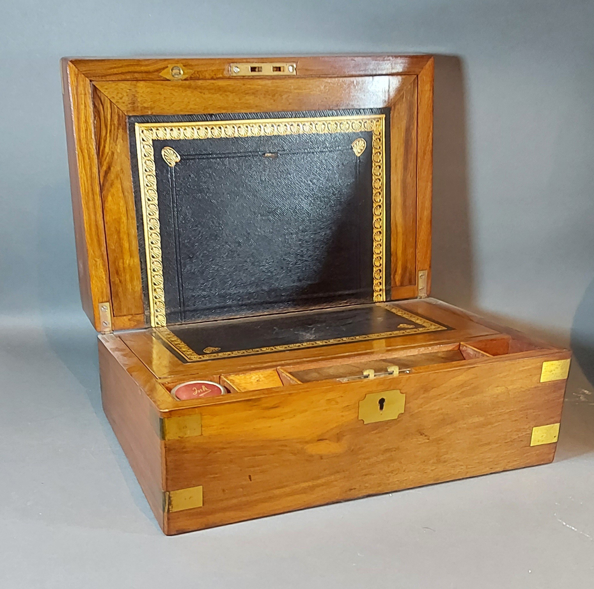 A 19th Century walnut brass banded fold over writing box, the hinged cover enclosing a fitted