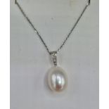 An 18ct white gold pearl and diamond pendant set with three diamonds above a large pear shaped pearl