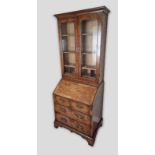 A George I style walnut bureau bookcase, the moulded cornice above to glazed doors enclosing