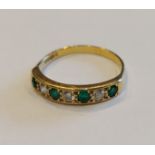 An 18ct gold diamond and emerald set band ring, with three diamonds and four emeralds, 2.8gms,