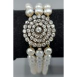 A triple row pearl choker, the large clasp set with a central Diamond surrounded by three tiers of