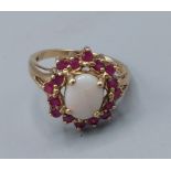 A 9ct gold opal and ruby set ring, with a cabachon opal surrounded by rubies, 3.1gms, ring size M