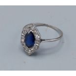 An Art Deco white metal ring set with a central Sapphire surrounded by Diamonds of hexagonal form,