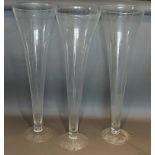A set of three large glass spill vases of tapering form, 80cms tall
