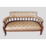 A late Victorian walnut sofa, the upholstered and spindle back above a stuff over seat raised upon