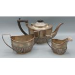 An Edwardian silver three piece tea service of half lobed form, comprising teapot, Birmingham 1903