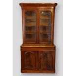 A Victorian mahogany bookcase, the moulded cornice above two arched glazed doors enclosing shelves