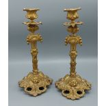 A pair of ormolu candlesticks in the rococo style decorated with cherub heads amounts foliage, 27cms