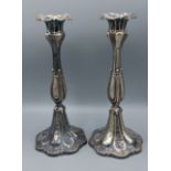 A pair of silver plated candlesticks with engraved embossed decoration, 27cms tall