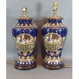 A pair of Continental table lamps decorated with reserves and highlighted with gilt upon a blue